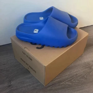 Blå Adidas Yeezy Slide sandaler - Säljer ett par blå Adidas Yeezy Slide sandaler, såklart äkta. Kvitto finns🧾 Skorna är aldrig använda och enbart testade därmed är de i mycket fint skick 10/10✅