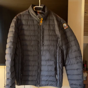 Svart dunjacka från Parajumpers L - Säljer en svart dunjacka från Parajumpers i storlek L. Jackan är superlätt, har quiltad design, dragkedja framtill och flera fickor. Klassisk patch på ärmen och snygga detaljer som orange ögla vid kragen. Perfekt för kalla dagar och riktigt stilren look. Inga hål eller slitnader i jackan den är som Ny.