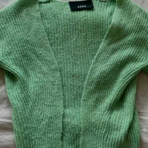 Ljusgrön stickad kofta - Stark ljusgrön stickad kofta från JJXX. Koftan har en öppen front utan knappar och är ribbstickad. Lite nopprig men inget man tänker på!