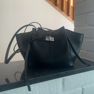 Svart väska från Gina tricot  - Stilren svart axelväska i skinn med snyggt silverfärgat spänne framtill. Den lilla modellen, nypris 400kr och i nyskick.