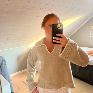 Beige stickad tröja med v-ringning   - Tröjan är i superbra skick endast använd en gång och är passande till alla outfits. Den är beige med lite vitt mönster nedtill och jättegosig. 