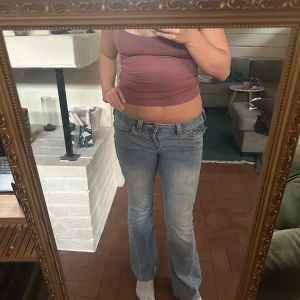 True Religion ljusblå bootcut jeans - Säljer ett par ljusblå jeans från True Religion med klassiska sömmar och snygga detaljer på bakfickorna. Modellen har låg midja och bootcut-ben, perfekt för dig som gillar en avslappnad men ändå trendig look. Jag har sytt upp jeansen o passar mig som är 165