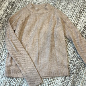 Beige/rosa stickad tröja från H&M  - Mysig stickad tröja från H&M BASIC i storlek XS. Tröjan har en rund halsringning, ribbade muddar och långärmad passform. Lite mer rosa i verkligheten. Har ett litet hål på ena ärmen
