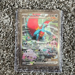 Roaring Moon ex - Cool och glittrig Pokémonkort med Roaring Moon ex! Perfekt för samlare och spelare som vill ha en kraftfull och snygg kort i sin samling. Kortet har unika attacker och färgstark design som sticker ut i leken.