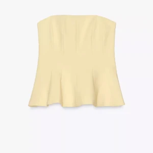 Gul topp från Zara - Supersnygg ljusgul korsett-topp med axelbandslös design och utsvängd nederdel. Toppen har en stilren och modern look som ger en cool siluett. Perfekt att styla med jeans eller kjol för en trendig vibe.