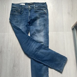 Replay Anbass Hyperflex jeans blå - Snygga Replay Anbass Hyperflex jeans i blå tvätt. Slim fit, vita kontrastsömmar och broderad logga på fickan. Stretchigt och skönt matreal. Om ni har frågor eller vid minsta fundering va inte blyga att skriva!