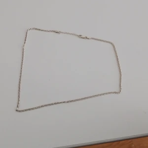 Tunt silverfärgat halsband - Säljer ett stilrent och tunt halsband i silverfärg med klassisk kedja och smidig karbinhake. Perfekt för dig som gillar minimalistiska smycken och vill ha något enkelt men snyggt runt halsen. Äkta silver kostar runt 1000/1500 ny men buda på det! Box tillkommer från albreksguld