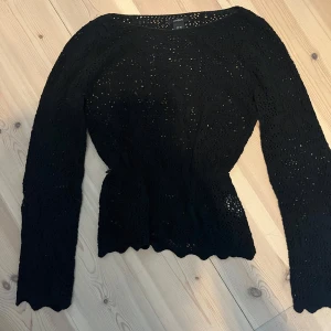 Svart spetsstickad tröja från Lindex - Supersnygg svart stickad tröja från Lindex i spetsmönster. Tröjan har lång ärm, markerad midja och vågig nederkant. Perfekt för dig som gillar en feminin och trendig look. Passar till både jeans och kjol!