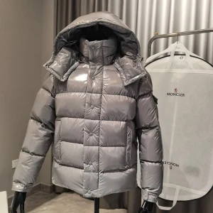 ÄKTA! Moncler Jacka - Snygg och glansig silverfärgad dunjacka från Moncler med stor huva och quiltad design. Jackan har Moncler-logga på ärmen, dragkedja och knappar framtill samt praktiska fickor. Perfekt för kalla vinterdagar när du vill sticka ut med stil. Priset går att förhandla vid väldigt snabb affär! 