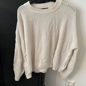 Oversized beige stickad tröja - Säljer en oversized stickad tröja i beige med grov ribbstickning och rund hals. Tröjan har långa ärmar och en avslappnad passform som är perfekt för lager-på-lager. Enkel och stilren design som funkar till allt.