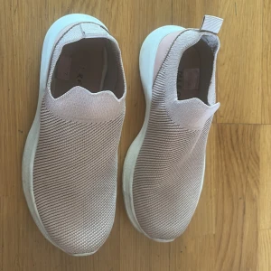 Ljusrosa slip-on sneakers - Snygga ljusrosa slip-on sneakers med stickad ovandel och vit platt sula. Skorna har en modern, minimalistisk look och är superenkla att ta på tack vare den elastiska designen. Perfekta för dig som gillar bekväma och stilrena skor till vardags.