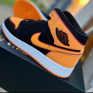 Nike Air Jordan 1 Mid orange/svart - Säljer ett par Nike Air Jordan 1 Mid i orange och svart med vita detaljer. Skorna har klassisk Jordan-logga på sidan, snörning och en orange yttersula. Kollar intresset, kom gärna med prisförslag!