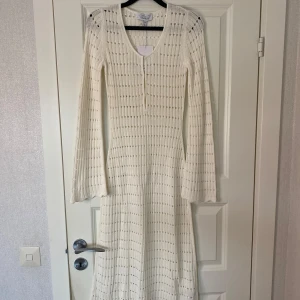 Vit stickad långklänning Other Stories - Superfin vit stickad långklänning från Other Stories med v-ringning. Klänningen har långa ärmar och ett genomgående hålmönster som ger en luftig känsla. Perfekt för vår och sommar när du vill ha något både bekvämt och snyggt. Nypris 990.