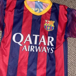 FC Barcelona Messi 10 matchtröja - Säljer en klassisk FC Barcelona fotbollströja med Messi 10 på ryggen. Tröjan har breda blå och röda ränder, gul krage och klubbmärke på bröstet. Qatar Airways som sponsor framtill. Perfekt för dig som älskar Barca och Messi.