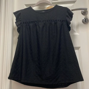 Svart spetsblus från SHEIN - Supersöt svart blus från SHEIN med broderade spetsdetaljer och volangiga korta ärmar. Blusen har rund halsringning och ett dekorativt band med blommönster! Passar bra som ett nattlinne eftersom det är väldigt luftigt och stort❤️