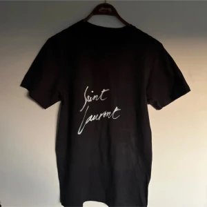Saint Laurent t shirt  - Riktigt fet och eftertraktad Saint Laurent t shirt i helt nytt skick! Är lite osäker på äktheten så därför är priset just nu på 499kr! nypris runt 4000kr. Storlek S. Tveka inte med att ställa frågor!