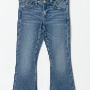 Blå bootcut jeans från Wrangler - Snygga blå bootcut jeans från Wrangler med klassisk femficksdesign och tydliga sömmar. Jeansen har normal passform, medelblå tvätt och ikonisk W-brodyr på bakfickorna. Perfekta för dig som gillar en retroinspirerad look med lite utsvängda ben. Använda men inget som syns, 