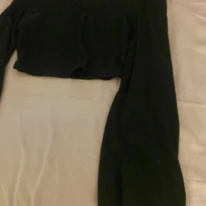 Svart croppad långärmad topp - En svart croppad topp med lång ärm och v-ringad hals. Enkel och stilren design som passar perfekt till höga jeans eller kjol. Mjuk och stretchig känsla, perfekt för dig som gillar en clean look.köpt för 80