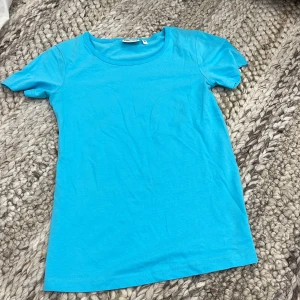 Blå t-shirt från Tribute - Blå t-shirt  i storlek S. T-shirten har rund halsringning och korta ärmar