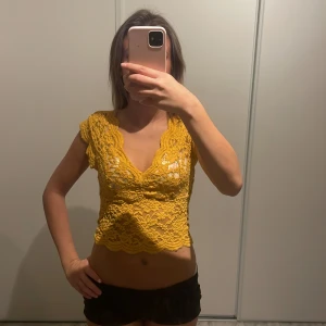 Gul spetslinne - Säljer ett snyggt gult spetslinne med blommigt mönster. Linnet är ärmlöst och croppat, perfekt för varma dagar.💕