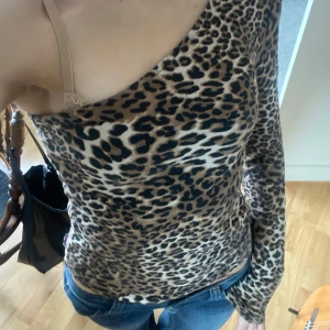 Leopardmönstrad oneshoulder topp - Säljer en snygg leopardmönstrad topp med oneshoulder-design och lång ärm. Tight passform som sitter riktigt snyggt och ger en cool vibe. Färgerna går i beige, brun och svart. Perfekt för dig som vill sticka ut lite extra.