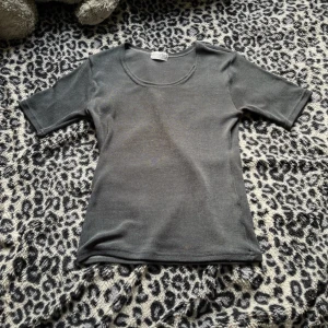 Mörkgrå basic topp med kort ärm - Enkel och stilren mörkgrå topp med rund halsringning och korta ärmar. Perfekt att matcha med jeans eller kjol för en clean look. Mjuk och stretchig känsla, passar dig som gillar minimalistisk stil.