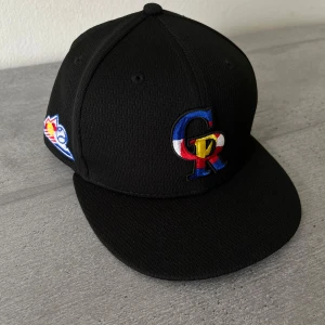 Colorado Rockies svart keps New Era - Svart 59FIFTY keps från New Era med Colorado Rockies broderad logga i blått, rött, vitt och gult framtill. Snygga broderade patchar på sidorna och baksidan. Kepsen är tillverkad i 100% polyester och har klassisk rak skärm.