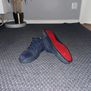 Mörkblå mockasneakers från Louboutin - Snygga mörkblå sneakers i mocka från Louboutin med klassiska röda sulor. Skorna har rund tå, platt sula och snörning framtill. Perfekta för dig som vill sticka ut med exklusiva detaljer och lyxig känsla.du får med dig påsen såklart till dem vill du ha bild på den så får du skriva så fixar ja till dig även kort finns om du vill ha det.säljer för jag har köpt Valentinos och it längre använder dem. Pris kan diskuteras!!
