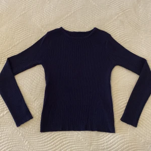 Mörkblå ribbad stickad tröja - En stilren mörkblå stickad tröja med ribbad struktur och rund hals. Tröjan har lång ärm och en slim passform som sitter snyggt på kroppen. Perfekt att matcha med jeans eller kjol för en clean look.💕💕Tyvärr finns inte etiketten kvar på tröjan då jag har klippt av den.🤗