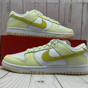 Nike Dunk Low vit/gul sneakers - Nike Dunk Low i vitt och gult med trendig tie-dye-look. Läder med gula mockadetaljer och fräsch sommarkänsla – perfekta sneakers för dig som vill sticka ut!
