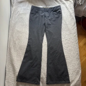 Grå lågmidjade bootcut kostymbyxor  - Snygga grå kostymbyxor från ONLY i bootcut-modell. Väldigt lågmidjade. Storlek 40 (L) men skulle säga att det är mer en storlek 38 (M)