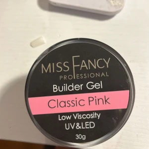 Miss Fancy Builder Gel Classic Pink - Använd på endast 2 fingrar. Builder Gel från Miss Fancy i färgen Classic Pink. Gelen har låg viskositet och funkar med både UV- och LED-lampa. Perfekt för att bygga snygga naglar med en naturligt rosa ton. Kommer i en rund burk på 30g.