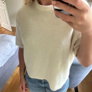 Vit stickad tshirt kortärmad tröja - Supermjuk och krämvit stickad tröja med korta ärmar och rund hals. Tröjan har en avslappnad passform och är perfekt att styla med jeans eller kjol. Enkel och stilren design som funkar året runt.