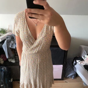 Blommig omlottklänning XOXO Friends - Supersöt kort blommig klänning från XOXO Friends(Ullared) med omlott och v-ringning. Ljus bas med små blommor i pastellfärger, kort ärm och volangkant nertill. Perfekt för sommarens alla tillfällen!