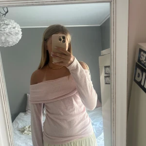 Ljusrosa offshoulder långärmad tröja - Superfin ljusrosa offshoulder tröja med långa ärmar och bred krage som vilar snyggt över axlarna. Mjuk och skön, perfekt för dig som vill ha en enkel men ändå trendig look. Passar till både jeans och kjol.