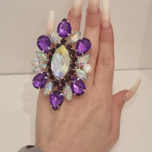 Stor lila statementring med kristaller - En riktigt maffig statementring med stora lila och iriserande kristaller i olika former. Ringen har en blomliknande design och gnistrar rejält, perfekt för dig som vill sticka ut. Sätt pricken över i:et på din outfit med denna unika accessoar!