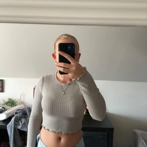 Grå croppad ribbad tröja FB Sister - Säljer en grå croppad långärmad tröja från FB Sister (New Yorker) i ribbat material. Tröjan har en tight passform, rund halsringning och vågig kant nertill och vid ärmslut. Perfekt till jeans eller kjol för en chill och trendig look.