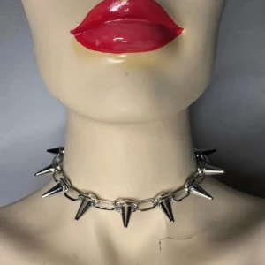 Silvrigt chokerhalsband med spikes Justerbar storlek Nytt & oanvänt Alternativ Punk Rock Metal Goth  - Kraftfull choker i silvrig metall med konformade spikes. Justerbar längd (ca 33–43 cm) gör att den passar perfekt för både vardag och fest. Perfekt för dig som gillar punk, goth, rock eller Y2K-stil. Halsbandet är nytt och oanvänt.  Ingen prutning – priset är redan lågt, men jag erbjuder rabatt vid köp av flera saker. Jag rensar smyckesskrin och garderob, så kika gärna på mina andra annonser också!  