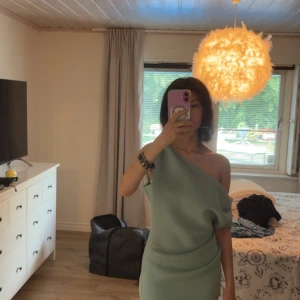 Ljusgrön one shoulder klänning - Säljer en stilren ljusgrön klänning med one shoulder-design. Klänningen är kort och har en tight passform som framhäver figuren. Perfekt för dig som vill sticka ut med en modern och trendig look. Är helt ny och har lapparna fortfarande på. Köptes från ASOS för ca 1000kr men säljs pga ingen användning. Hör gärna av er vid behov av mer bilder eller mer information🫶