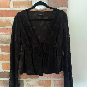Svart blommig fin blus  - Supersnygg svart blus med blommiga detaljer ifrån Gina trixig. Djup v-ringning och man kan knyta framtill hur man vill. Perfekt för att piffa till outfiten 💖