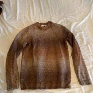 Brun stickad tröja från Kappahl - Mysig brunmelerad stickad tröja från Kappahl i storlek S. Tröjan har rund halsringning, långa ärmar och ribbade muddar vid ärmslut och nederkant. Perfekt för lager-på-lager och chill höststil.