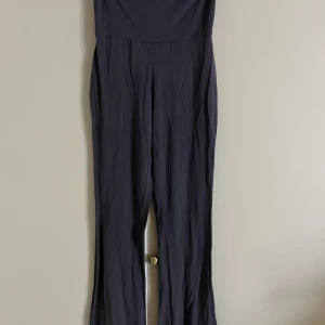 Svart byxdress från Gina Tricot XS - Säljer en svart byxdress från Gina Tricot i storlek XS. Byxdressen har långa, raka ben och är tillverkad i ett mjukt och stretchigt material som sitter snyggt på kroppen. Perfekt för dig som gillar en stilren och enkel look.