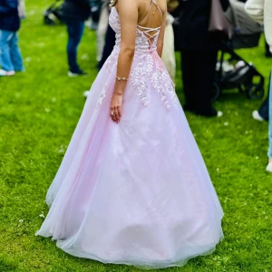 Rosa Balklänning  - Intressekoll på min balklänning. Storleken är runt 32-34. Finns även snörning i ryggen där man själv kan bestämma hur det vill sitta. Vi har sytt upp den. Jag är 160cm och den går ner på marken med en underkjol på mig. Underkjolen följer även med i köpet. Kontakta mig ifall ni har några frågor!