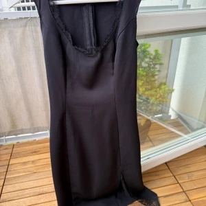 Svart elegant klänning i nyskick. Xs - •Elegant svart klänning med spetsdetaljer vid halsringningen och en diskret spetskant vid benslutet. •Klänningen har en figurnära passform och en smickrande silhuett. •Använd vid 1 tillfälle, som ny. •Storlek Xs.  •Tvättad. Djurfritt och rökfritt hem.