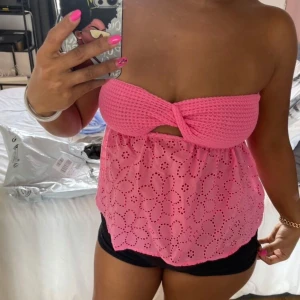 Rosa tubtopp med virkad överdel och broderade blommor - Säljer en söt rosa tubtopp med virkad överdel och broderade blommor på den nedre delen. Toppen är axelbandslös och har en twistdetalj framtill. Perfekt för sommardagar och festivaler! Lappen avklippt! Passar som S och även M då den är stretchig. Kan gärna sänka priset. ORDNARIE PRIS: 250kr
