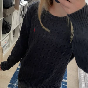 Mörkblå stickad tröja från Polo Ralph Lauren - Mörkblå kabelstickad tröja från Polo Ralph Lauren. Modellen är 12 år och 153cm