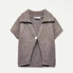 Brun stickad kofta från Zara - Säljer en brun stickad kofta med korta ärmar och en stor krage. Koftan har en knapp framtill och är perfekt att slänga över en t-shirt eller linne. Enkel och stilren design som passar till mycket.