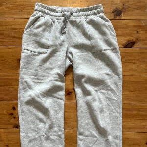 Ljusgrå mjukisbyxor - Säljer ett par ljusgrå mjukisbyxor från 157 med resår i midjan. Byxorna har två sidofickor och är tillverkade i mjukt bomullsmaterial, perfekta för en avslappnad stil.