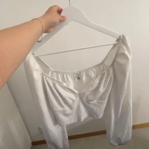 Vit offshoulder topp från Only - Säljer en vit offshoulder topp från Only. Toppen har lång ärm och är gjord i ett ribbat material som ger en snygg struktur. Perfekt för dig som gillar en trendig och stilren look.