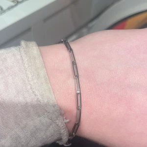 Tunt silverfärgat armband med avlånga länkar - Säljer ett stilrent och minimalistiskt armband i silverfärg med avlånga länkar. Perfekt för dig som gillar enkla och eleganta smycken. Passar till många olika stilar och är lätt att matcha med andra accessoarer.